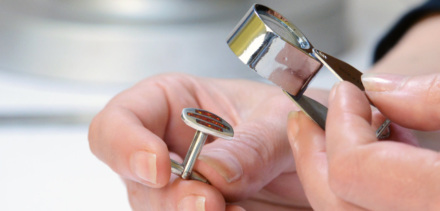 Inspecting Trinity Cufflink with loupe