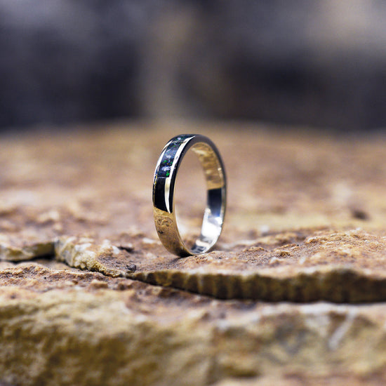 Opals & Ashes Circle Memorial Ring. White gold black fire. opals blended with our customers loved one’s ashes Photographed on rock