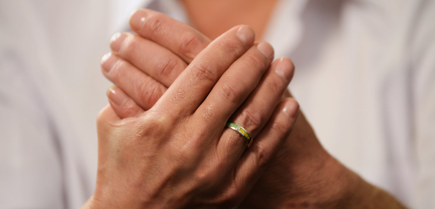 Opals & Ashes Rainbow Unisex Memorial Ring Silver. Ashes blended with Crushed Opals the colours of the rainbow. Green Yellow. Modelled on male hand.