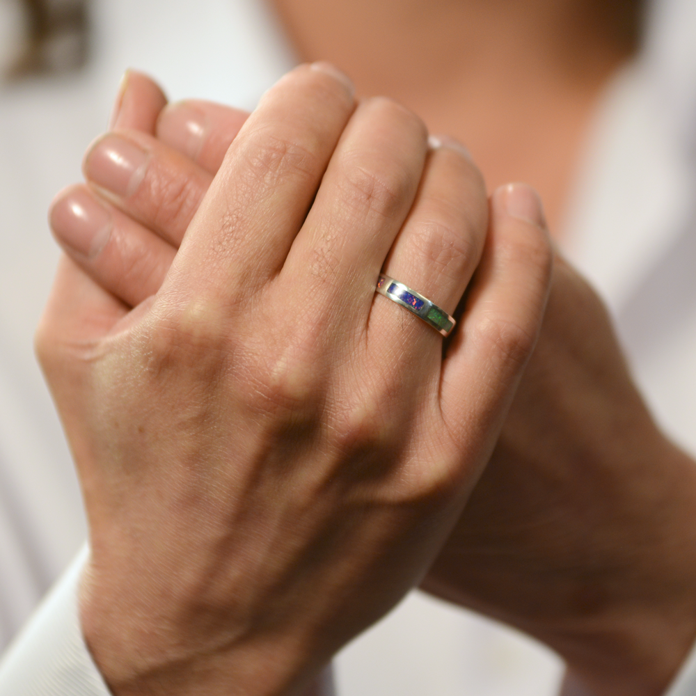 Opals & Ashes Rainbow Unisex Memorial Ring Silver. Ashes blended with Crushed Opals the colours of the rainbow. Green Purple. Modelled on male hand.