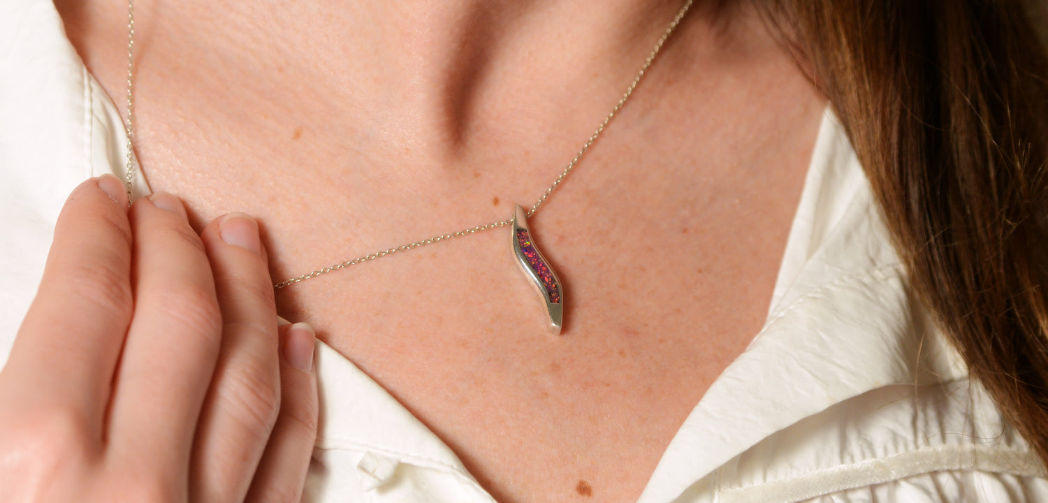 Opals & Ashes Wave Memorial Pendant Silver. Modelled on female. Ashes blended with Lavender Opals.